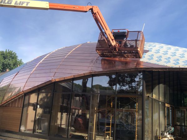 A copper roof with abstract roof lines on a radius surface gets installed